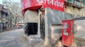 A building with a red sign in a foreign script, a black gate, and a red utility box. - Parle Inn Hotel (Mumbai)