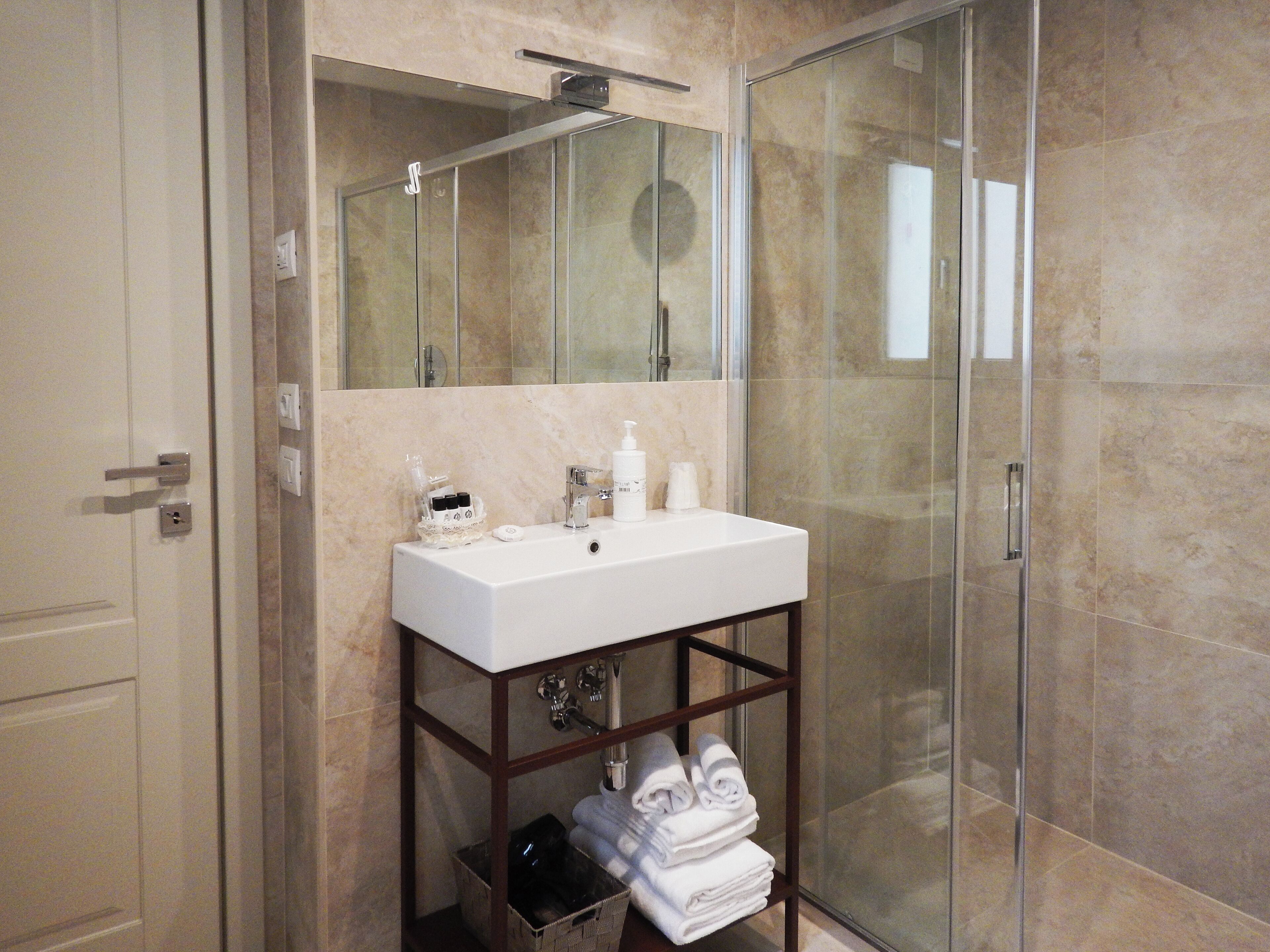 A bathroom with a white sink, mirror, and glass shower enclosure.