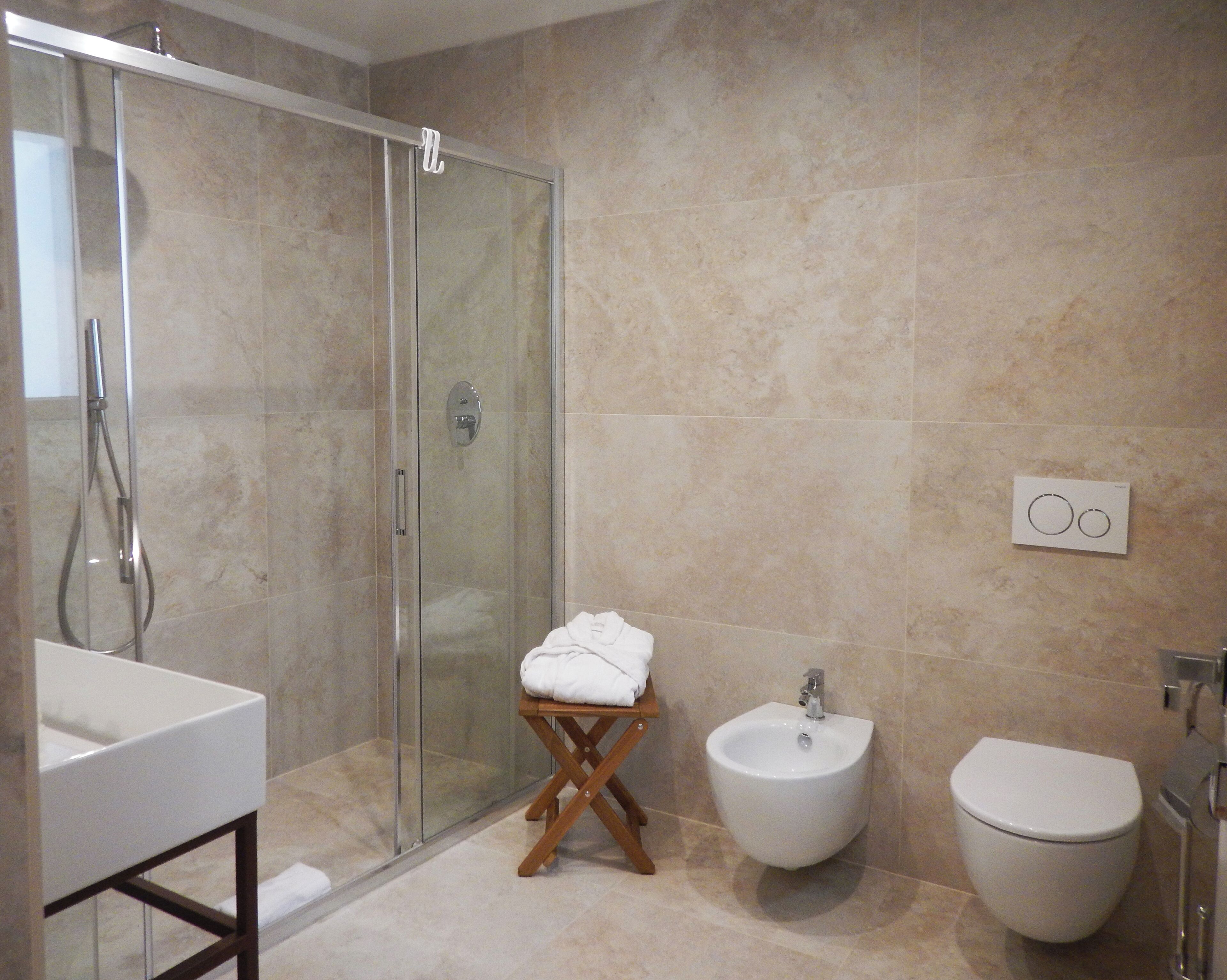 A modern bathroom with a glass shower enclosure, a bidet, a toilet, and a vanity with a sink.