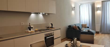 A modern kitchen with a dining area, a sofa, and a table with a magazine and candle.