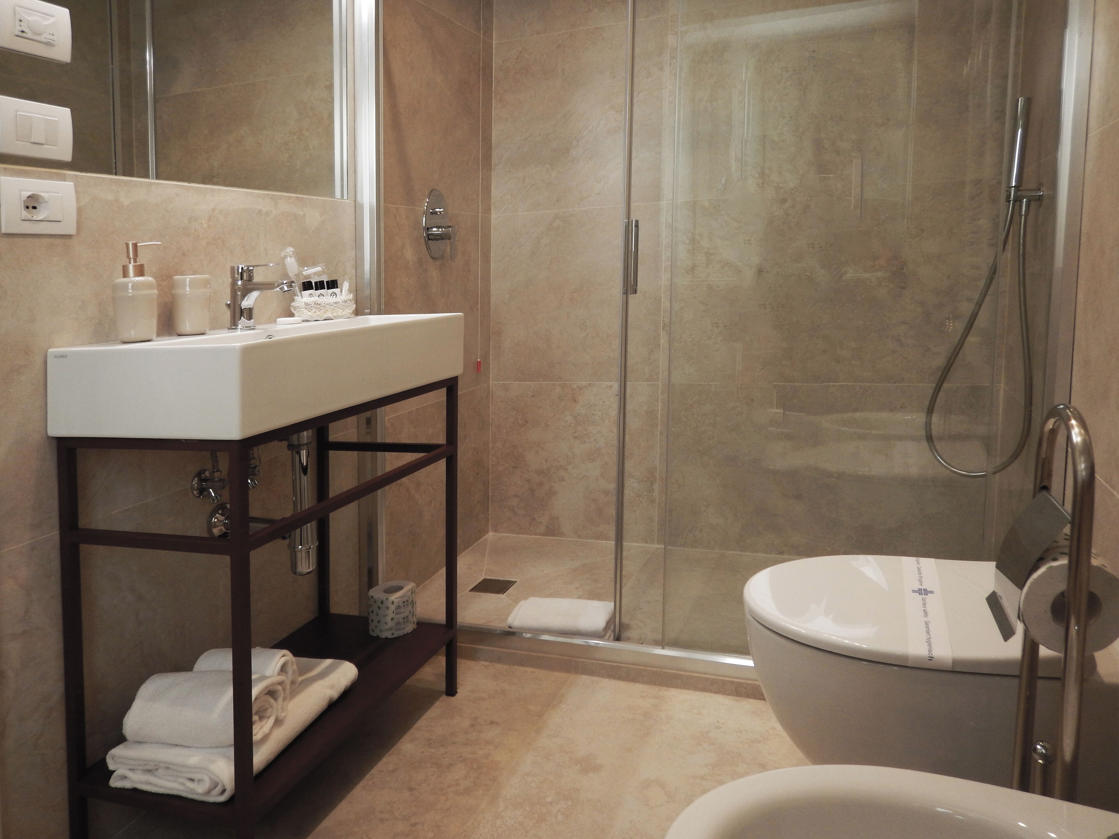 A modern bathroom with a white sink, mirror, and shower.