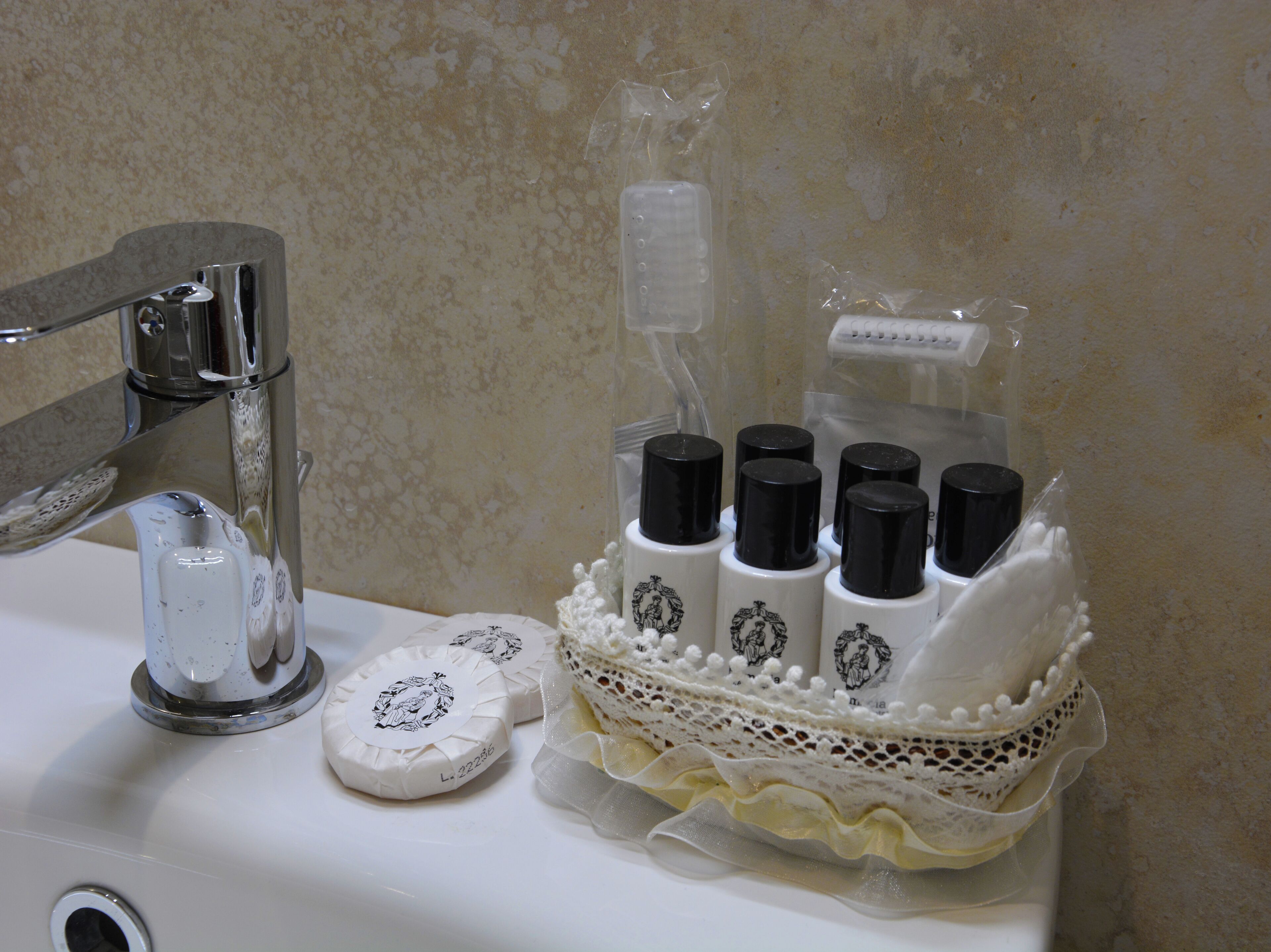 A bathroom sink with a faucet, soap, and a decorative container with bottles.