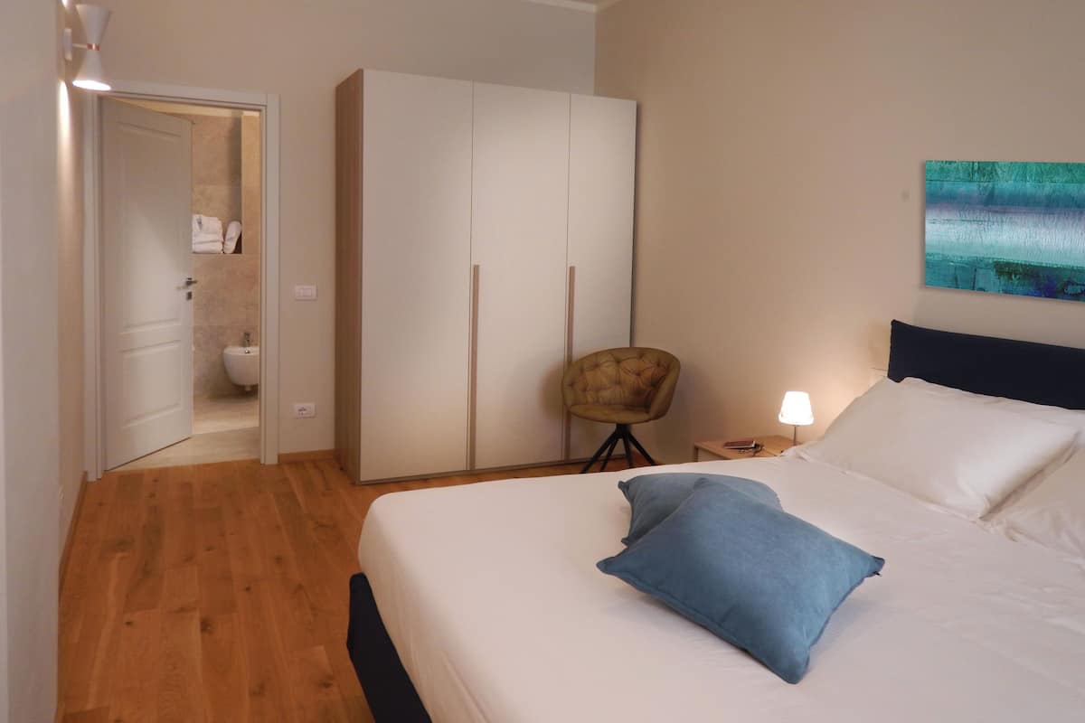 A bedroom with a bed, a wardrobe, a chair, and a nightstand.