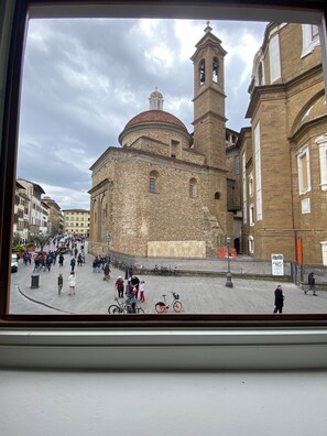 A historic building with a bell tower and dome, surrounded by a busy square with pedestrians and bicycles. - Chic Stay Boutique Apartments (Florence)