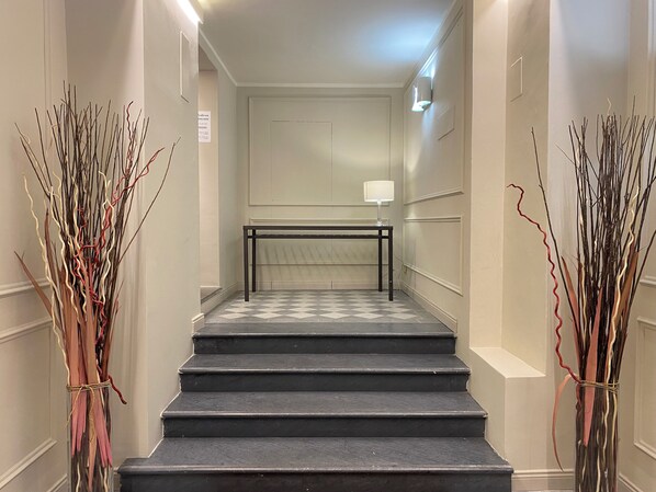 A staircase with a black railing, leading to a landing with a table and a lamp. - Chic Stay Boutique Apartments (Florence)