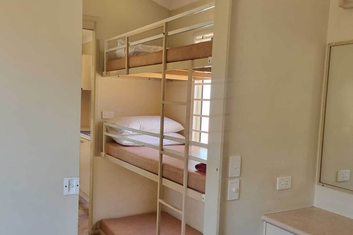 Une chambre avec des lits superposés, un petit bureau et un miroir.