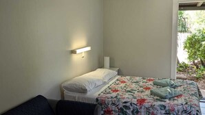 Una camera da letto con un letto, un comodino, un divano e una finestra vista verde.