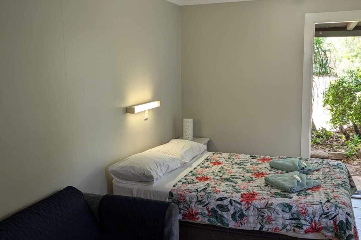 Une chambre à coucher comprenant un lit, une table de chevet, un canapé et une fenêtre donnant sur un paysage verdoyant.