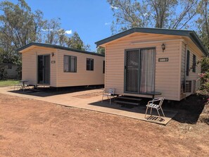 Two small, single-story cabins with a simple design, each featuring a door and a window. - Blackall Caravan Park (Blackall)
