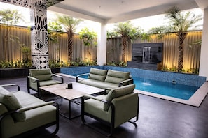 A poolside area with a seating arrangement, a small table, and a waterfall feature. - Atmosfera (Bengaluru)