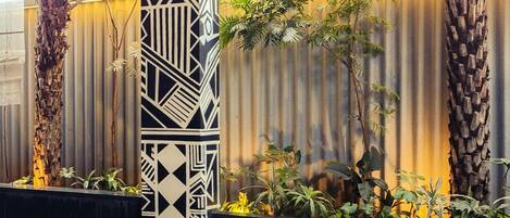 A pool area with geometric wall patterns, palm trees, and tiled flooring.