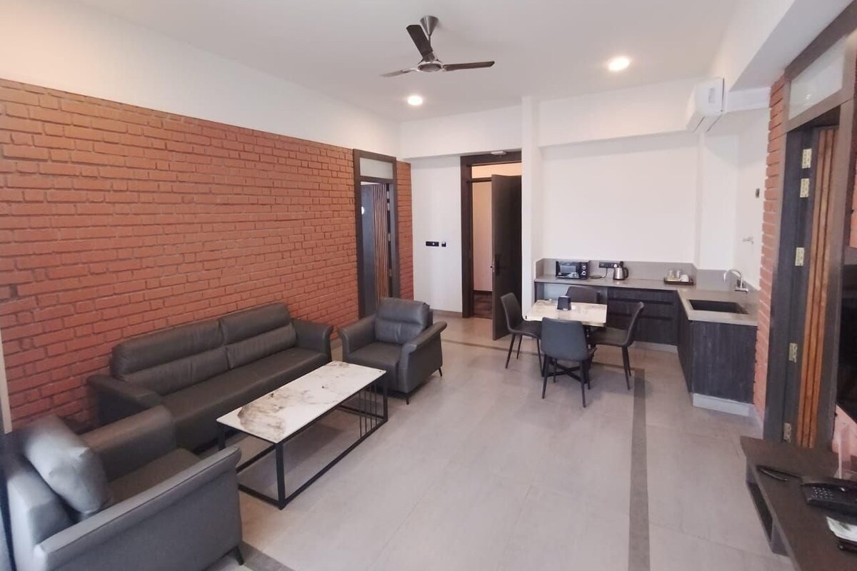 A modern living room with a sofa set, a coffee table, and a dining area with chairs and a kitchen counter.