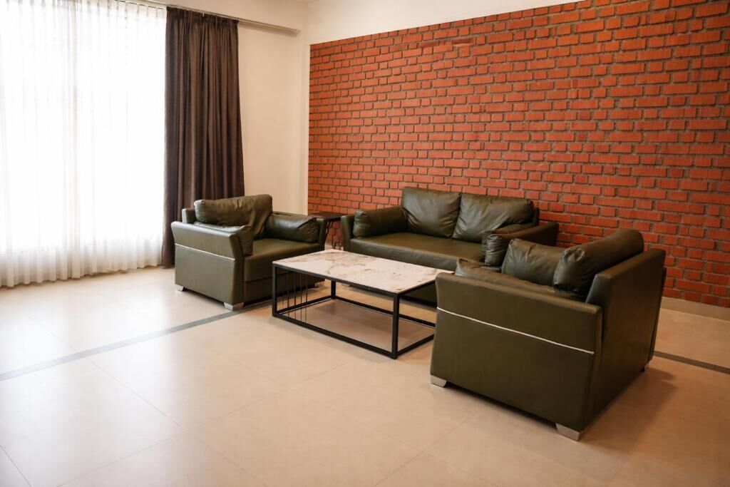 A living room with a brick wall, two leather sofas, a coffee table, and a window with curtains.