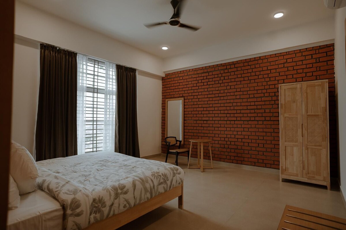 A bedroom with a bed, a chair, a small table, a mirror, and a wardrobe.