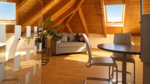 En modern lägenhet i loftstil med ett sluttande tak, en soffa, ett matbord och en krukväxt.