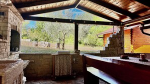 A rustic outdoor kitchen area with a stone floor, wooden beams, and a view of a green landscape. - Casa Robinson Nature Wifi Istria Croazia (Vizinada)