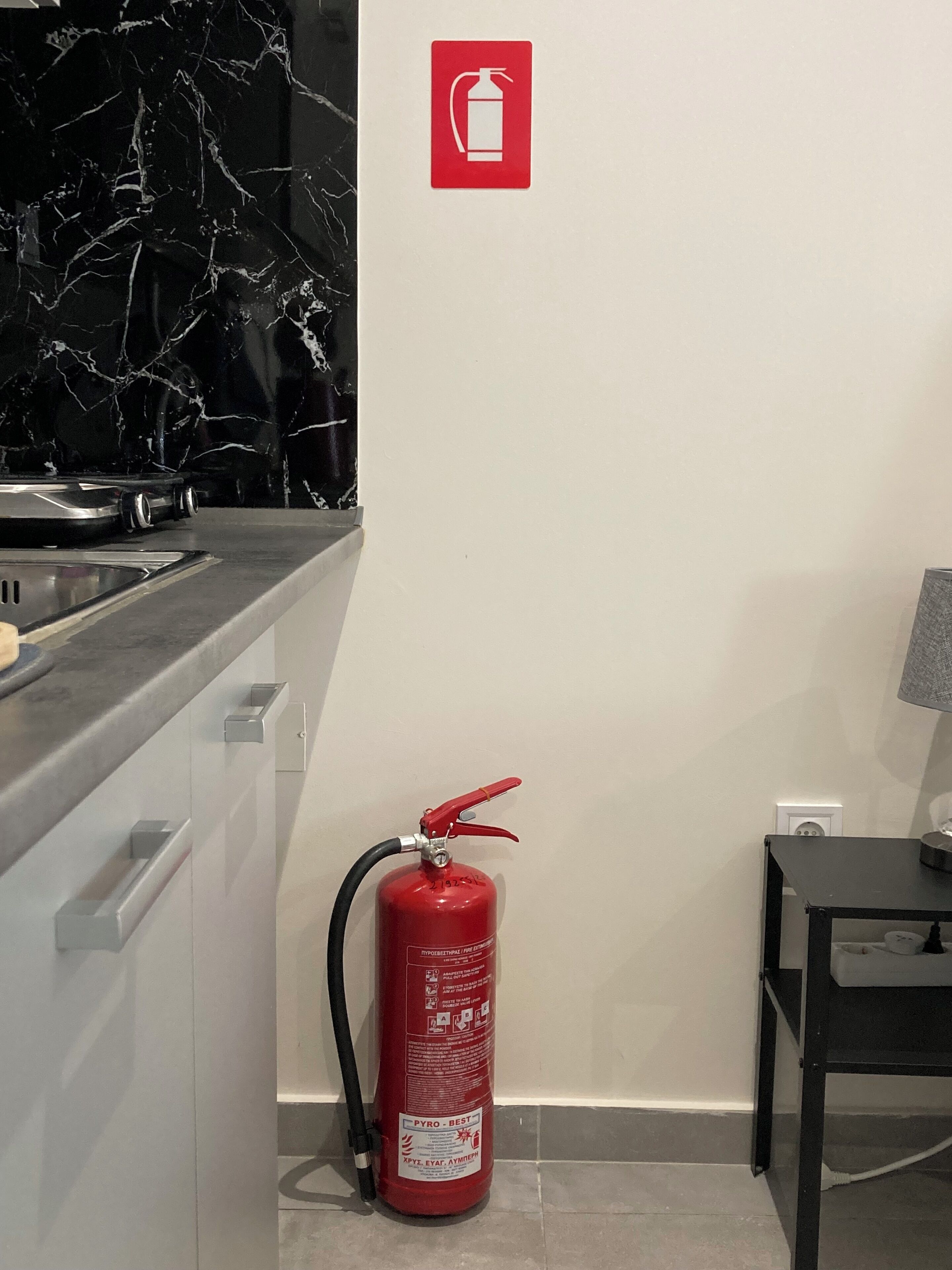 A kitchen with a fire extinguisher mounted on the wall and a sink.