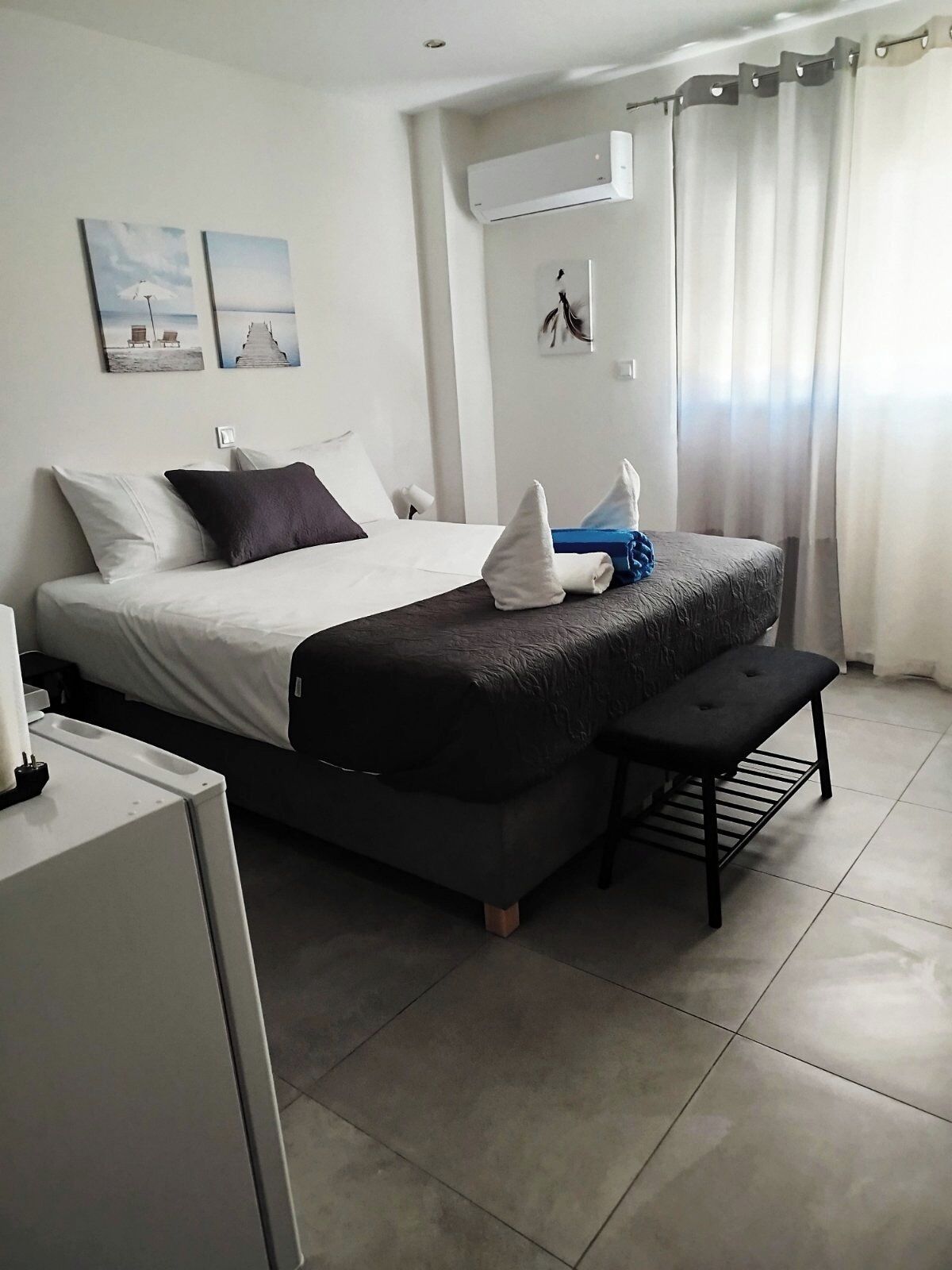 A modern hotel room with a bed, bedside table, and a small bench.