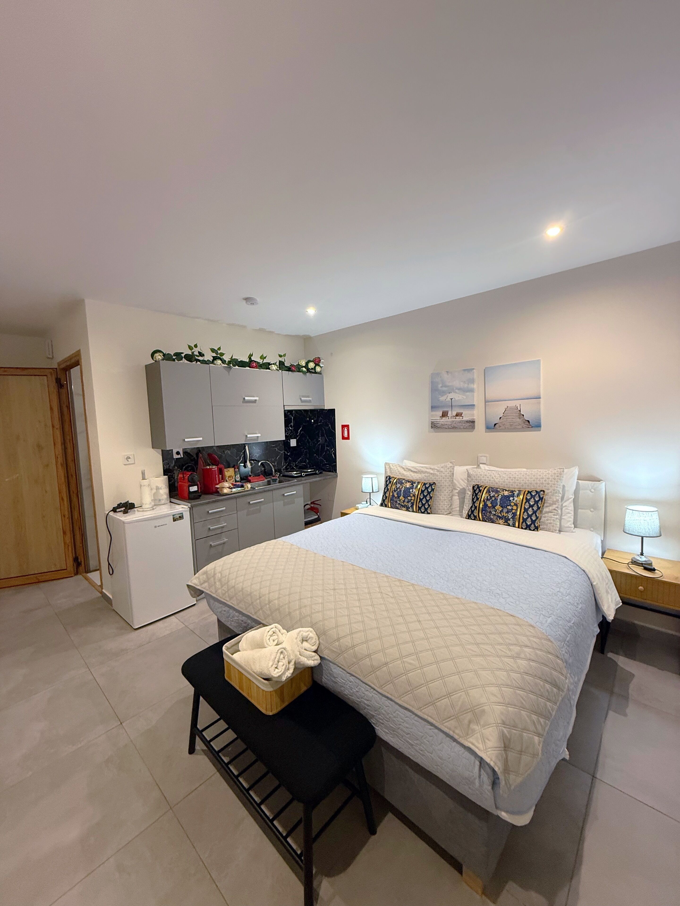 Un dormitorio moderno con una cama grande, un pequeño espacio kitchenette y un baño.