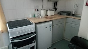 A compact kitchen with a stove, microwave, toaster, and a small refrigerator. - Seaside Escape at Withnell Road (Blackpool)