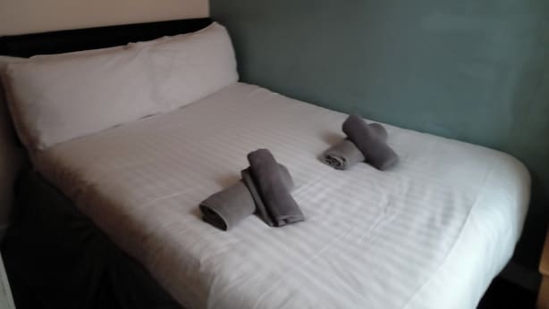 A neatly made bed with white linens and two rolled-up towels placed on the bed. - Seaside Escape at Withnell Road (Blackpool)