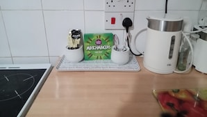 A kitchen counter with a coffee maker, a box of Matchmakers, and a kettle. - Seaside Escape at Withnell Road (Blackpool)