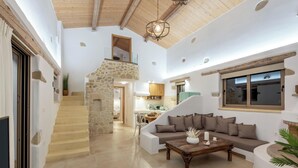 A spacious living area with a stone staircase, a sofa set, and a wooden coffee table. - Villa Froudi (Kissamos)