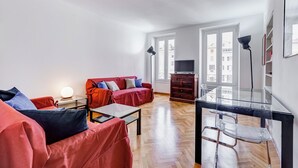 A modern living room with a red sofa, a glass coffee table, and a TV on a wooden cabinet. - Luminous Apartment few steps P.za Navona (Rome)