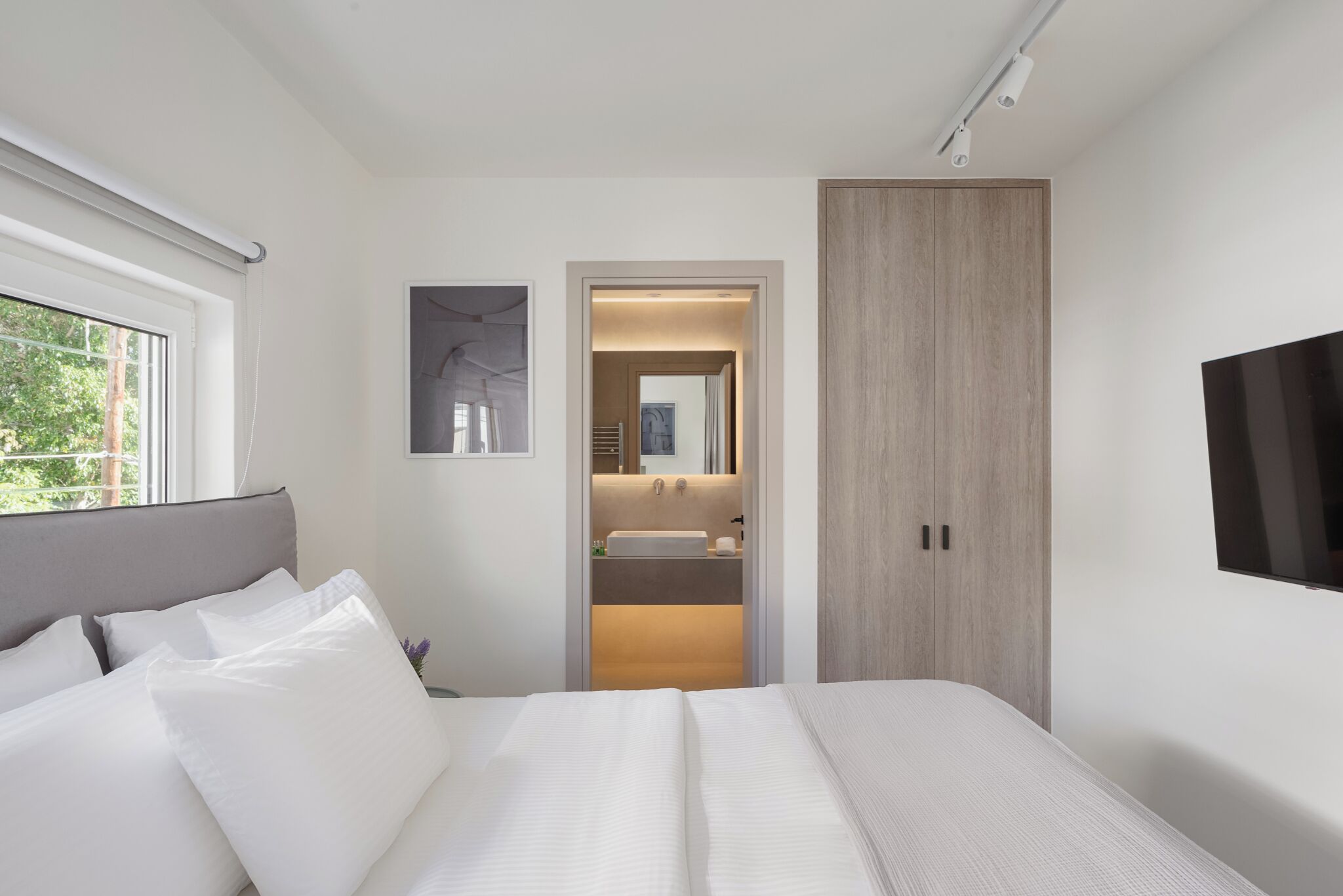 Een moderne slaapkamer met een groot bed, een nachtkastje, een spiegel en een kledingkast.