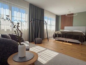 Ein modernes Schlafzimmer mit einem Bett, einem Sofa, einem Couchtisch und einem Fenster mit Vorhängen.
