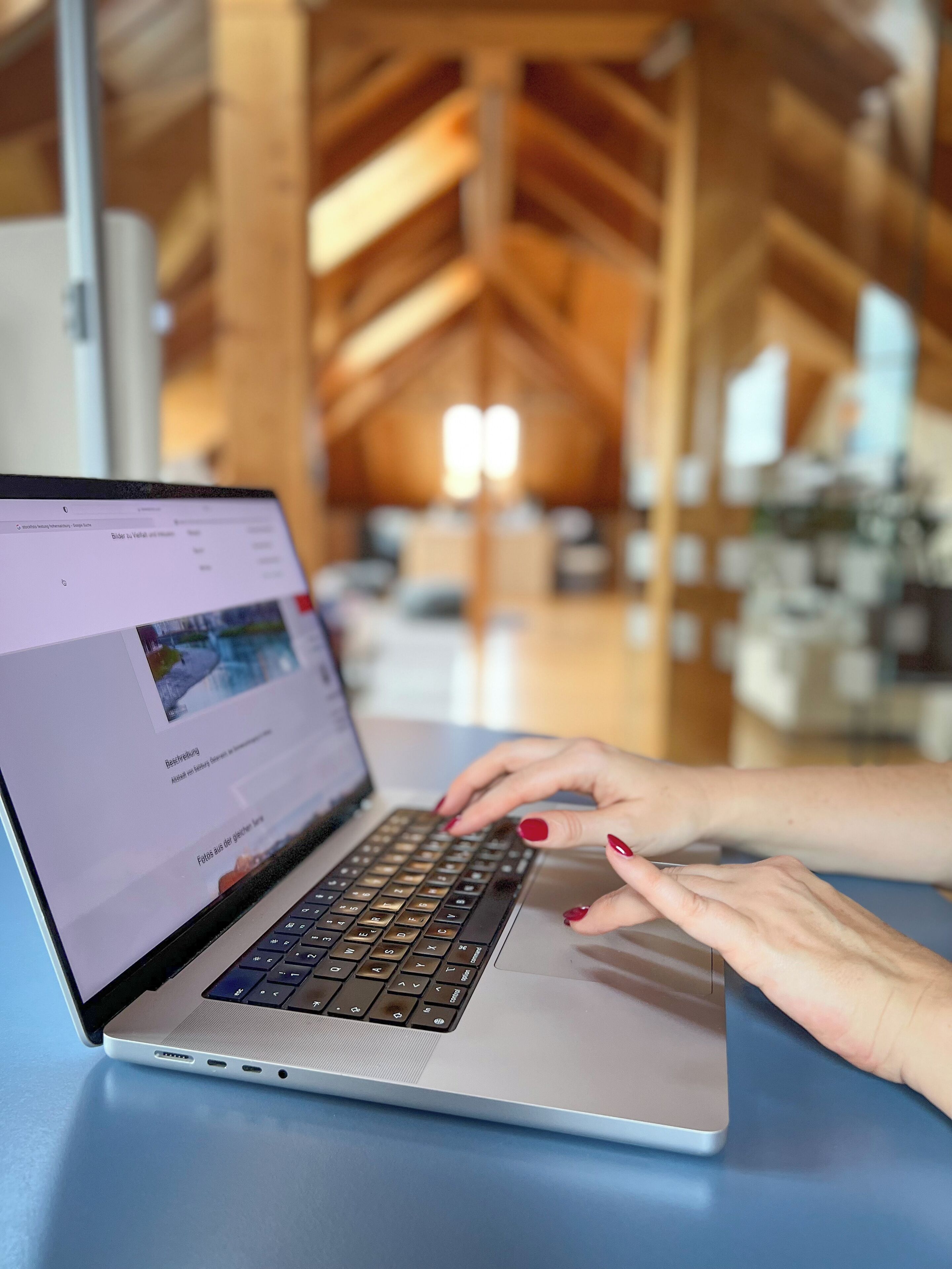 A laptop on a table with a wooden ceiling structure in the background.