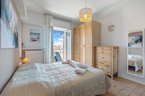 A bedroom with a bed, a wooden wardrobe, a hanging light fixture, and a view through an open door. - Maderno Sweet Home (Toscolano Maderno)
