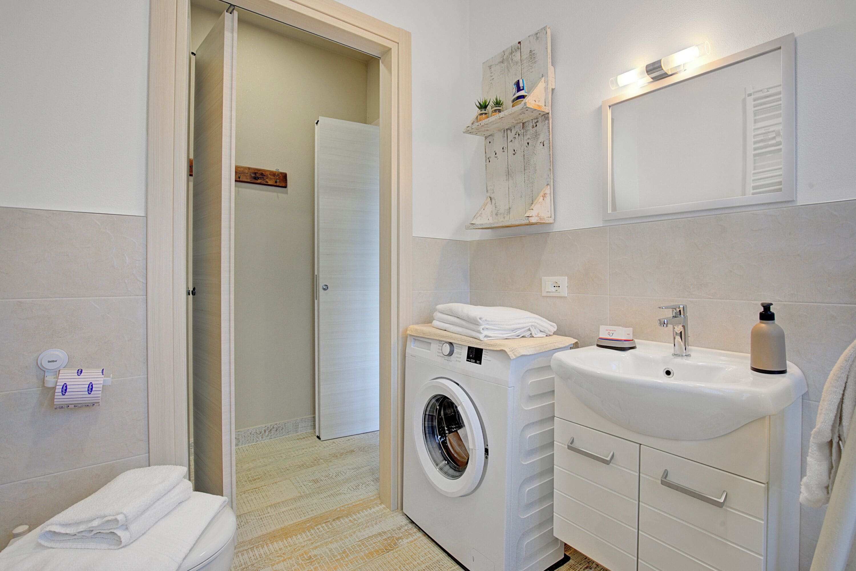 Une salle de bain moderne équipée d’un lave-linge, d’un évier et d’un miroir.