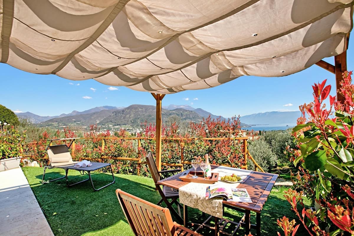An outdoor seating area with a table, chairs, and a pergola with a canopy.