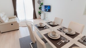Una sala de estar moderna con comedor, un sofá, un televisor y un reloj en la pared.
