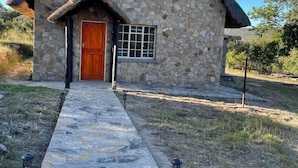 A stone building with a thatched roof, a wooden door, and a window. - Lovely 3 bed House in Juliasdale - 2273 (Nyanga)
