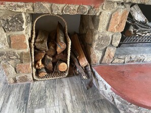 A stone fireplace with a woven basket filled with logs. - Lovely 3 bed House in Juliasdale - 2273 (Nyanga)