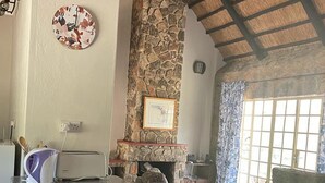 A kitchen with a granite countertop, a stone fireplace, and a dining area with a sofa and table. - Lovely 3 bed House in Juliasdale - 2273 (Nyanga)
