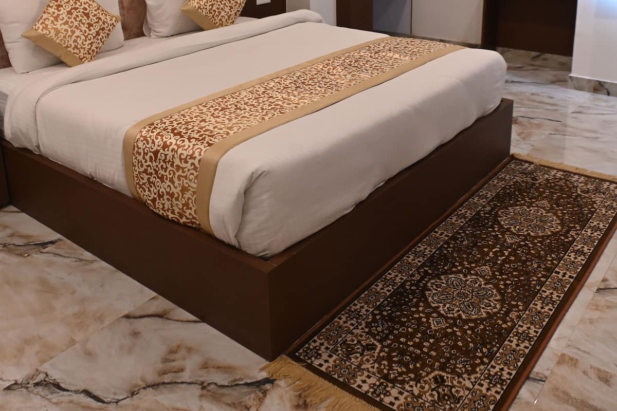 A modern bedroom with a large bed, a headboard, a nightstand, a mirror, and a wardrobe.