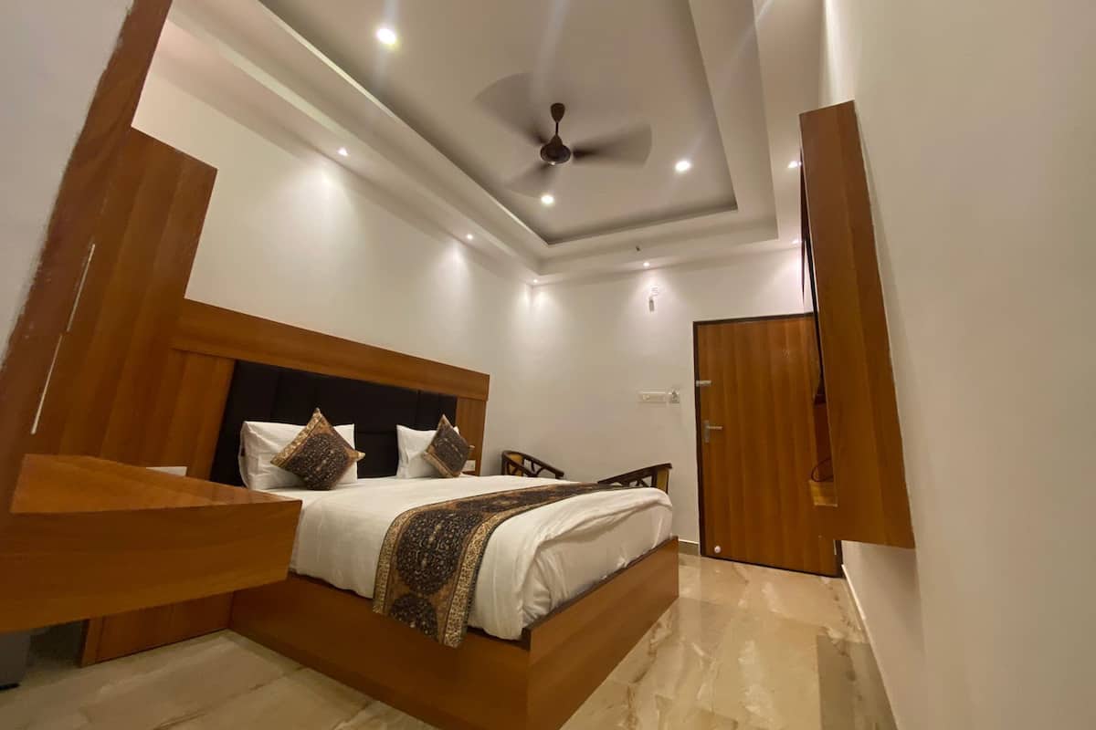 A modern bedroom with a wooden headboard, a bed with patterned bedding, a ceiling fan, and recessed lighting.