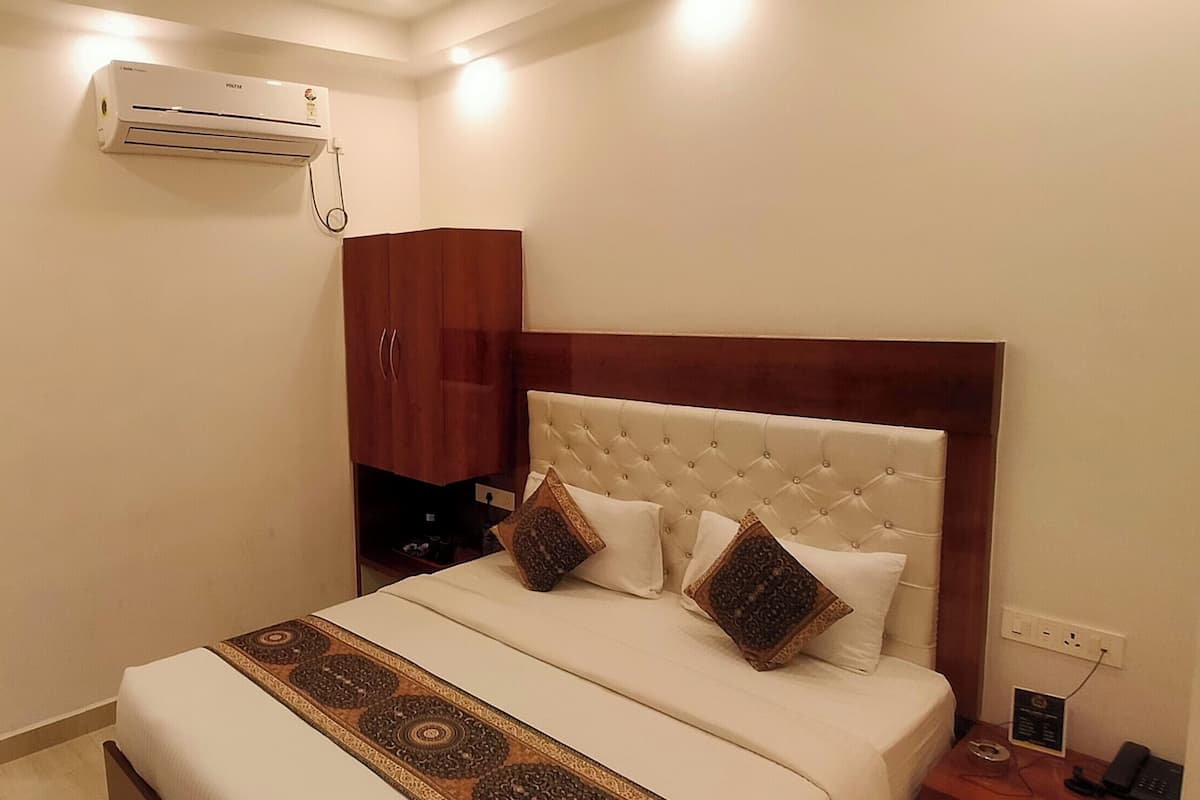 A bedroom with a bed, a wardrobe, an air conditioning unit, and a patterned wall.