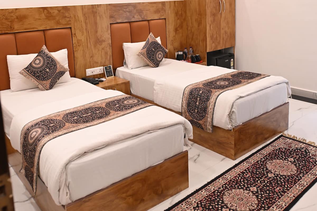 A hotel room with two beds, a wooden headboard, a large rug, and an air conditioning unit.