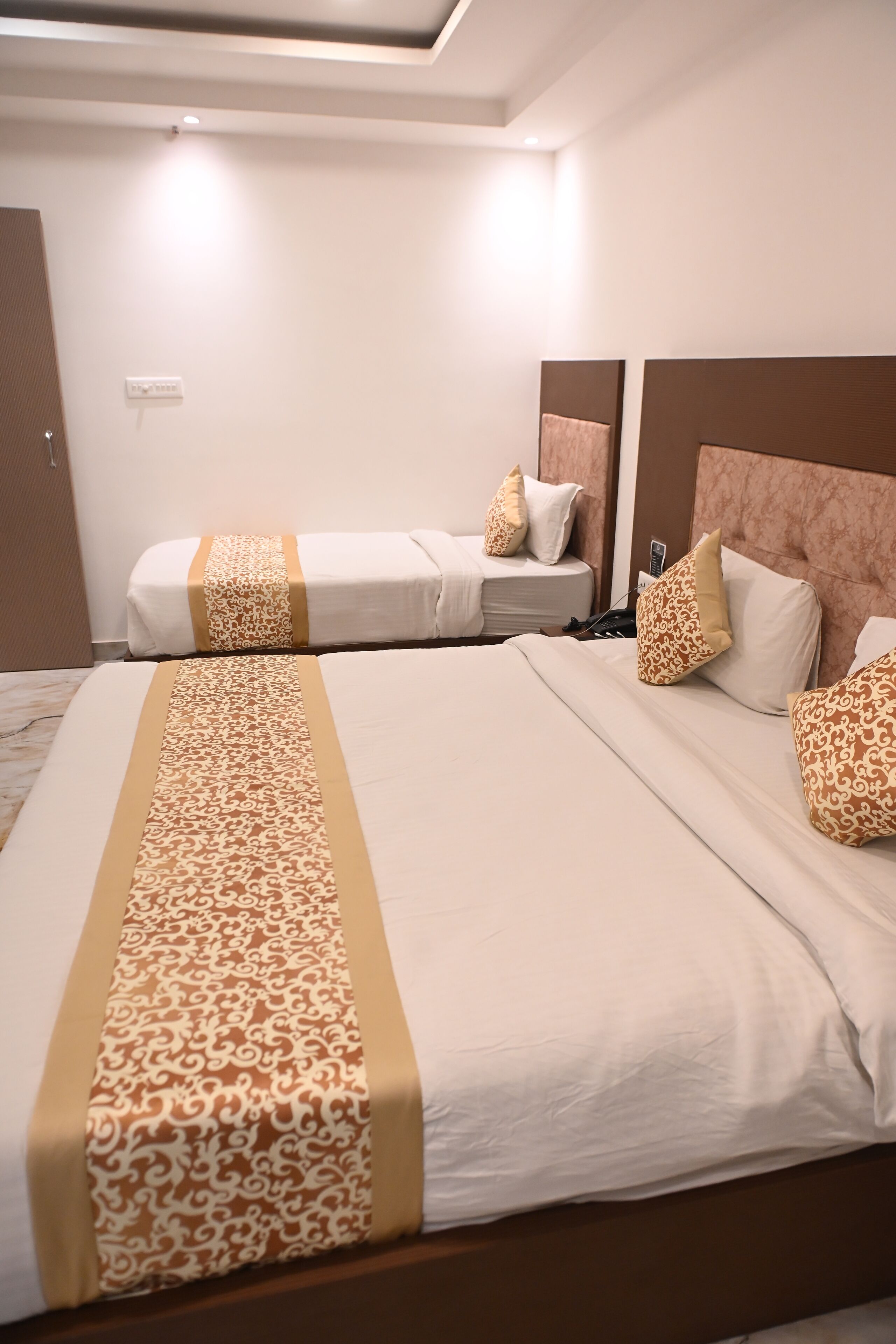 A hotel room with a large bed, a smaller bed, and a nightstand with a lamp.