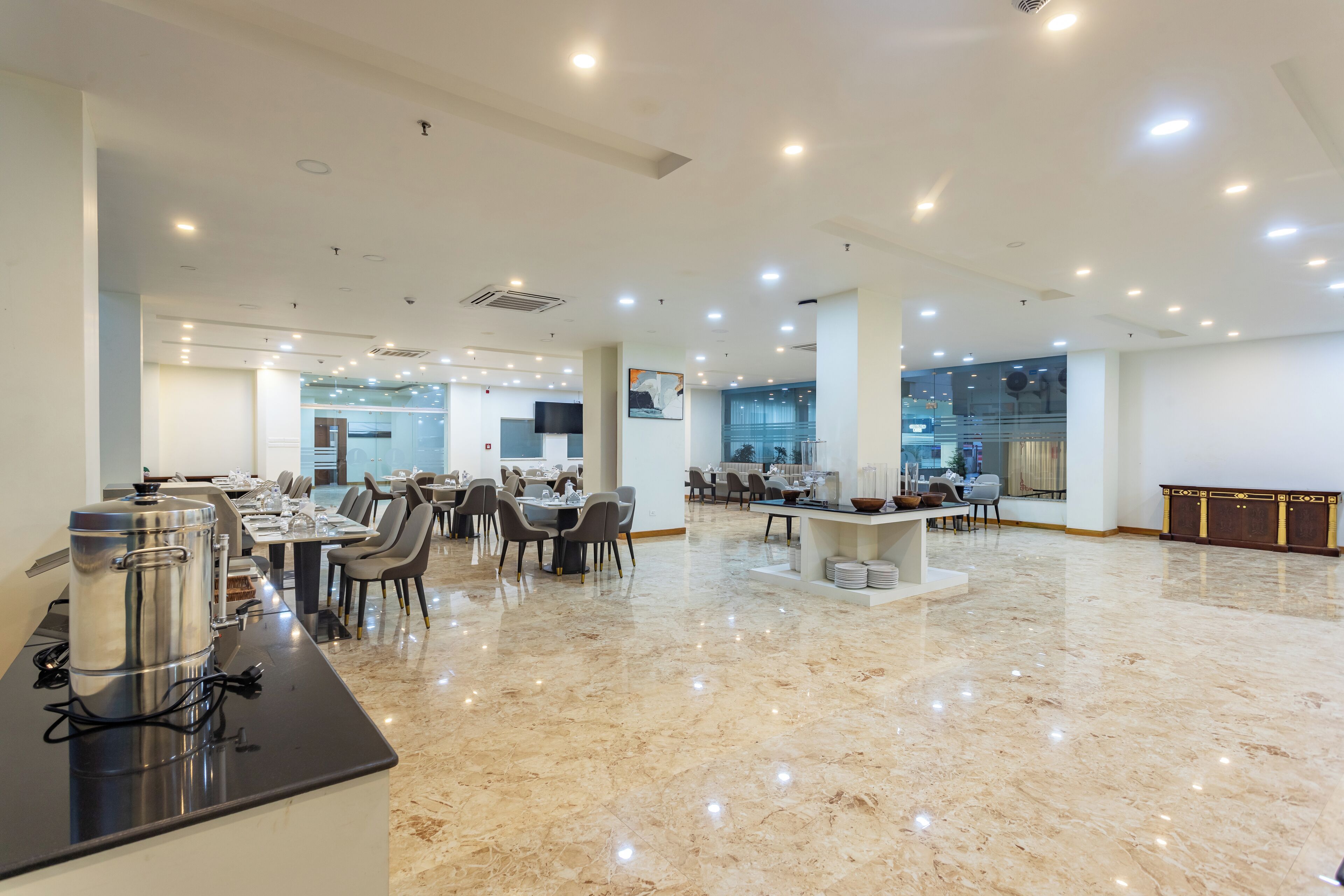 Un'ampia hall dell'hotel con pavimento in marmo lucidato, diverse aree ristorazione e una reception centrale.
