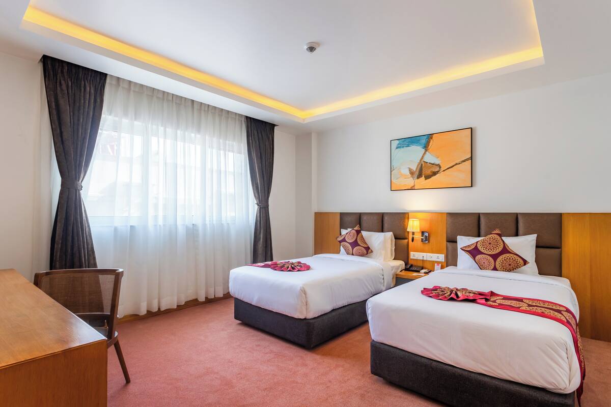 Habitación de hotel con dos camas, un escritorio y una silla.