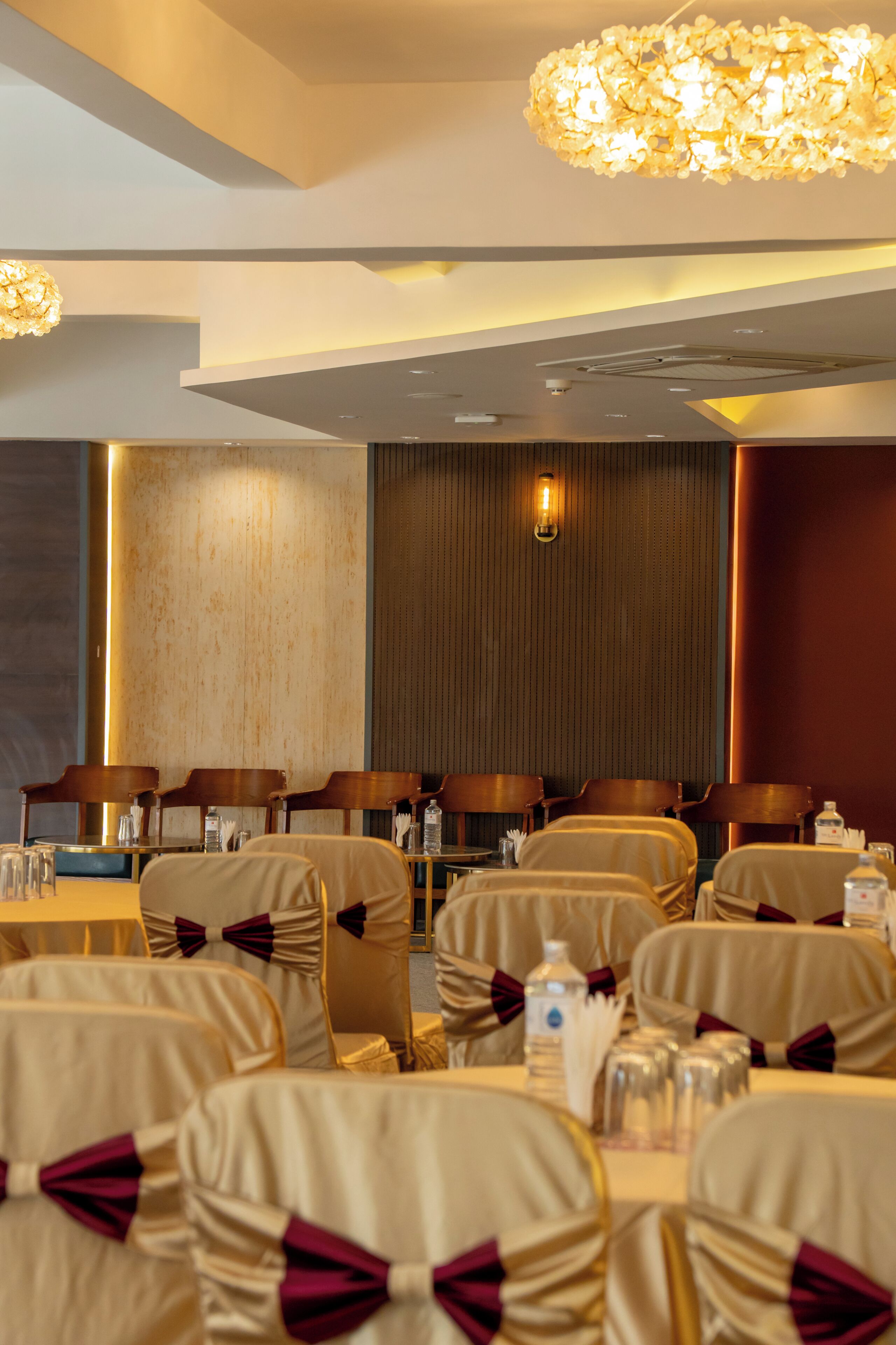 A conference room with tables and chairs, a chandelier, and a wall-mounted light fixture.