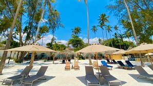 A beach with sun loungers and umbrellas, surrounded by palm trees. - Royal Mandarin Hotel & Resort Zanzibar (Kiwengwa)