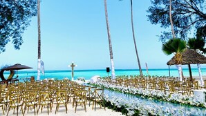 A beach wedding setup with rows of chairs and a white floral aisle. - Royal Mandarin Hotel & Resort Zanzibar (Kiwengwa)