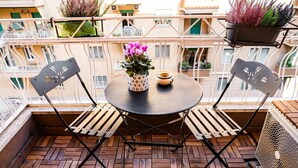 A round table with two chairs on a wooden deck, a potted plant, and a small bowl on the table.