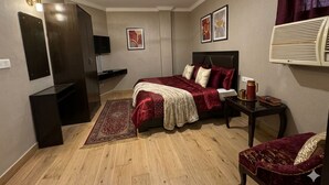 A bedroom with a bed, bedside table, and a ceiling fan. - Shoba Residency  (New Delhi)